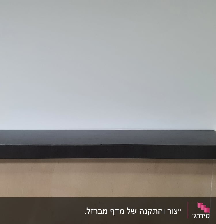 מדף עץ עם חלק מרכזי שחור על קיר לבן